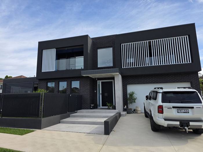 Modern black brick home exterior with white timber screening